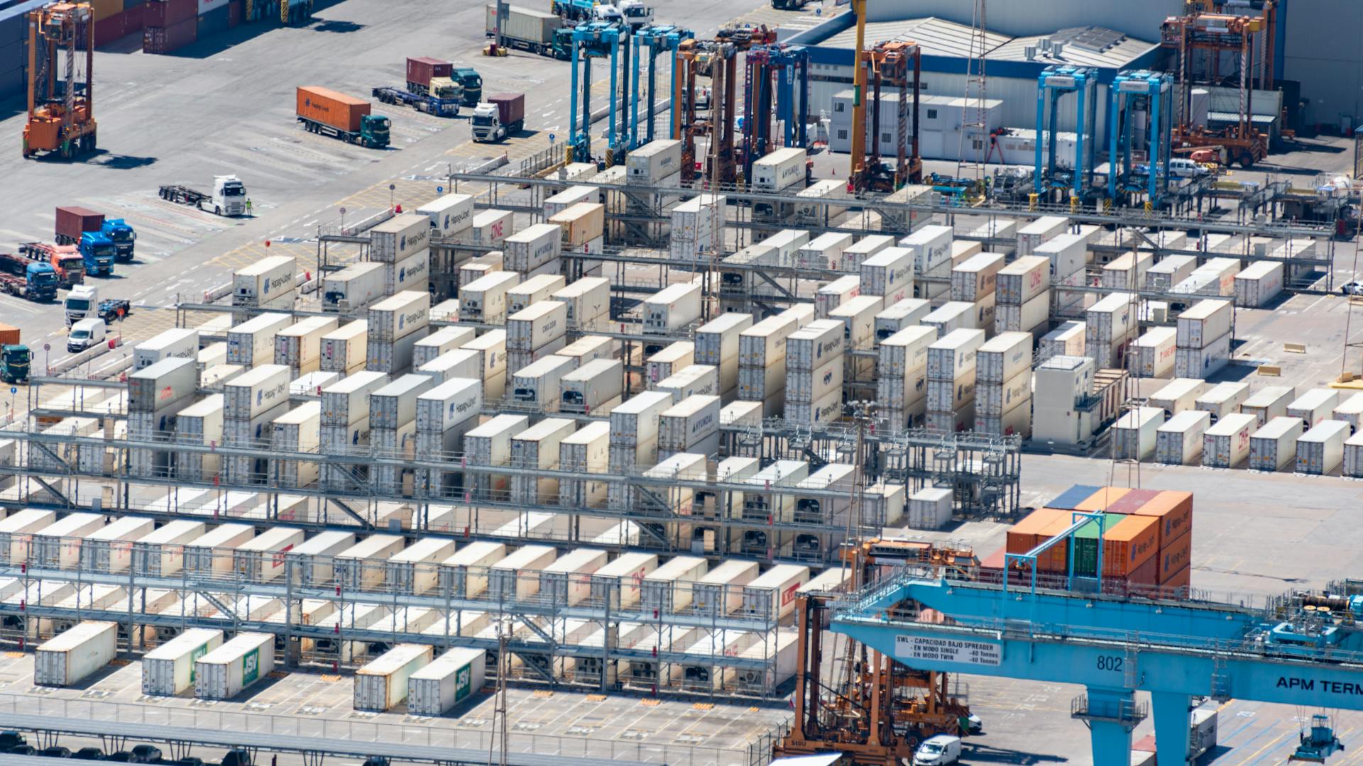 Bird's eye view of a logistics warehouse with shipping containers and trucks.