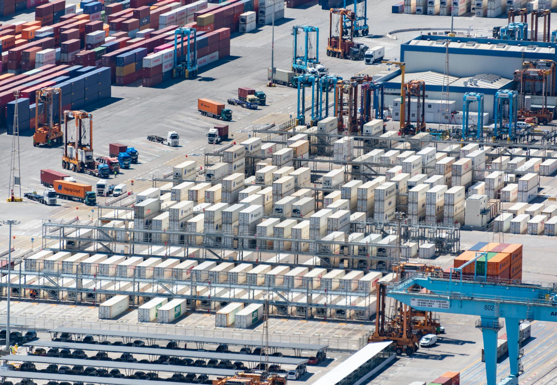 An aerial image showcasing a bustling cargo port with stacked containers and logistics machinery.
