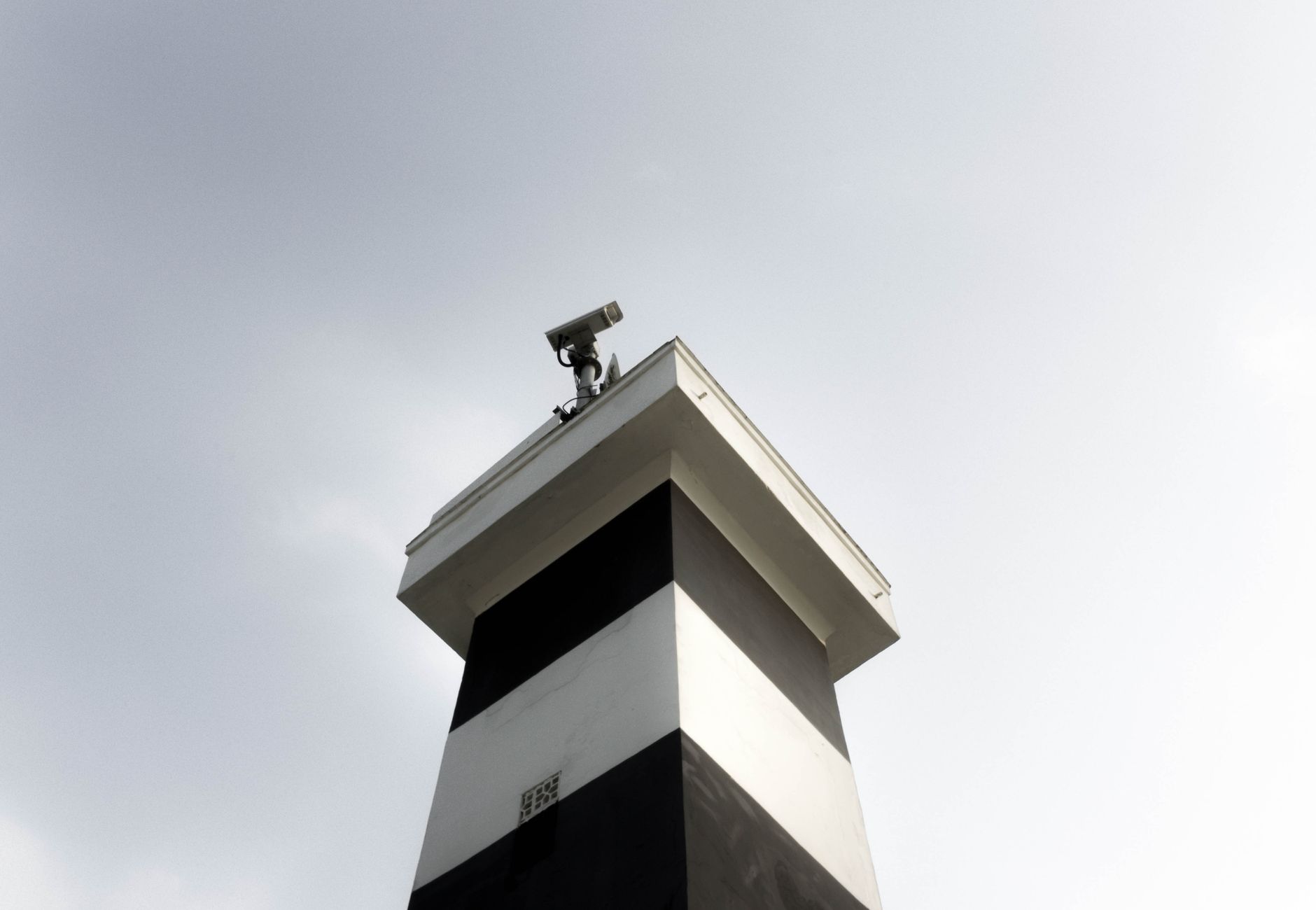 A modern surveillance tower equipped with a CCTV camera against a clear sky, showcasing security and technology.