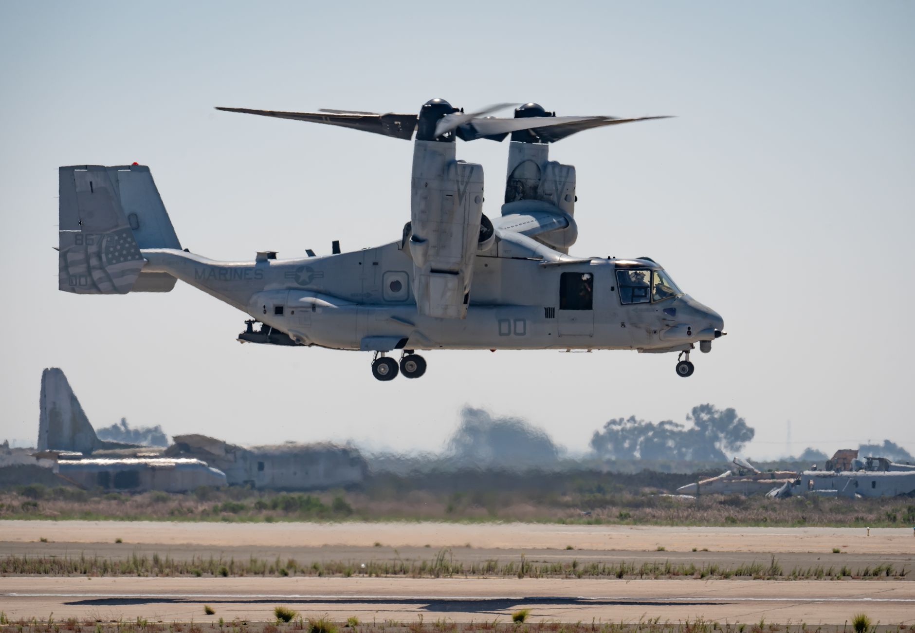 Military Bell Boeing V-22 Osprey aircraft flying over Miramar, CA runway.
