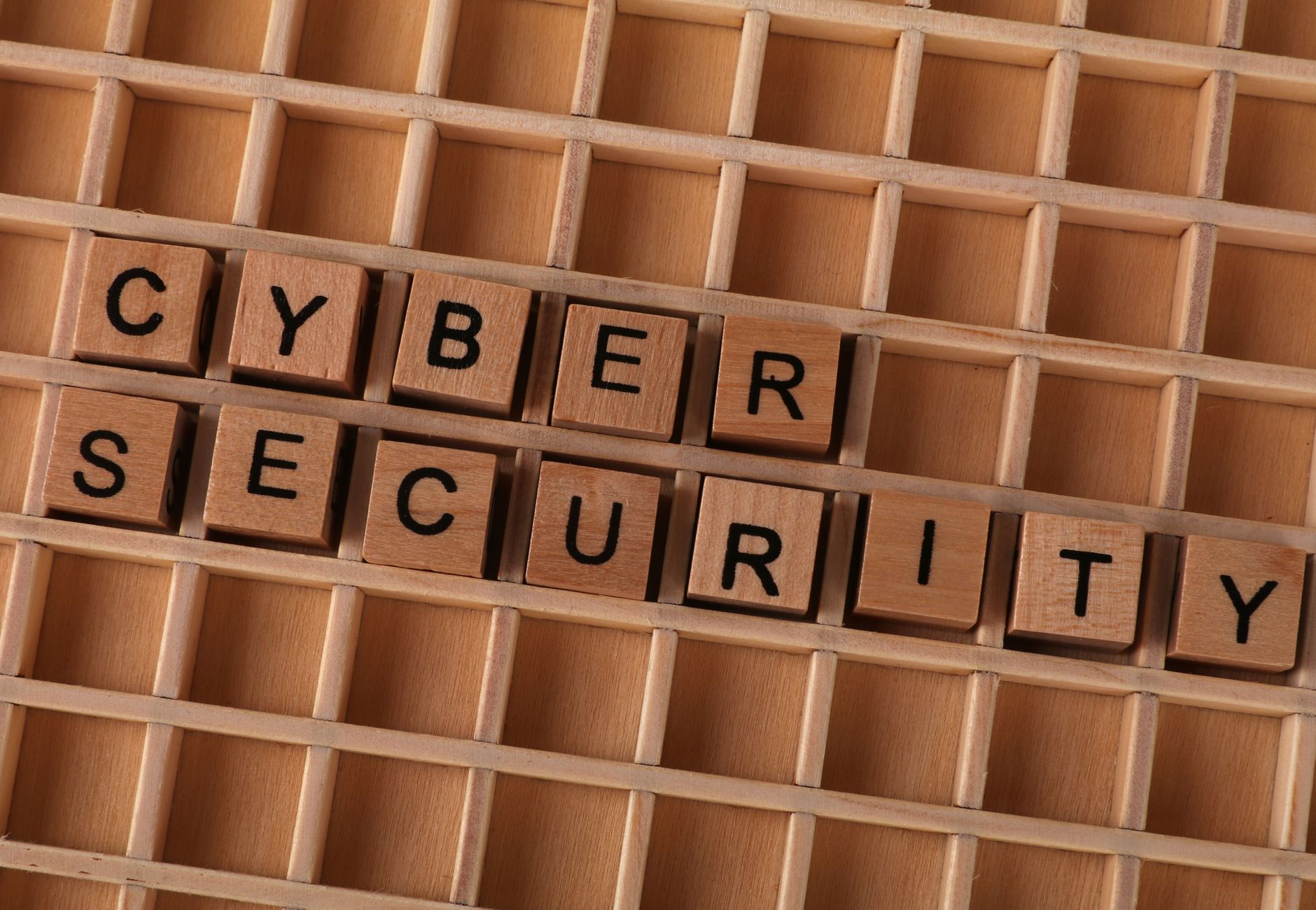 Wooden letter blocks spelling 'CYBER SECURITY' on a wooden grid background for data protection themes.