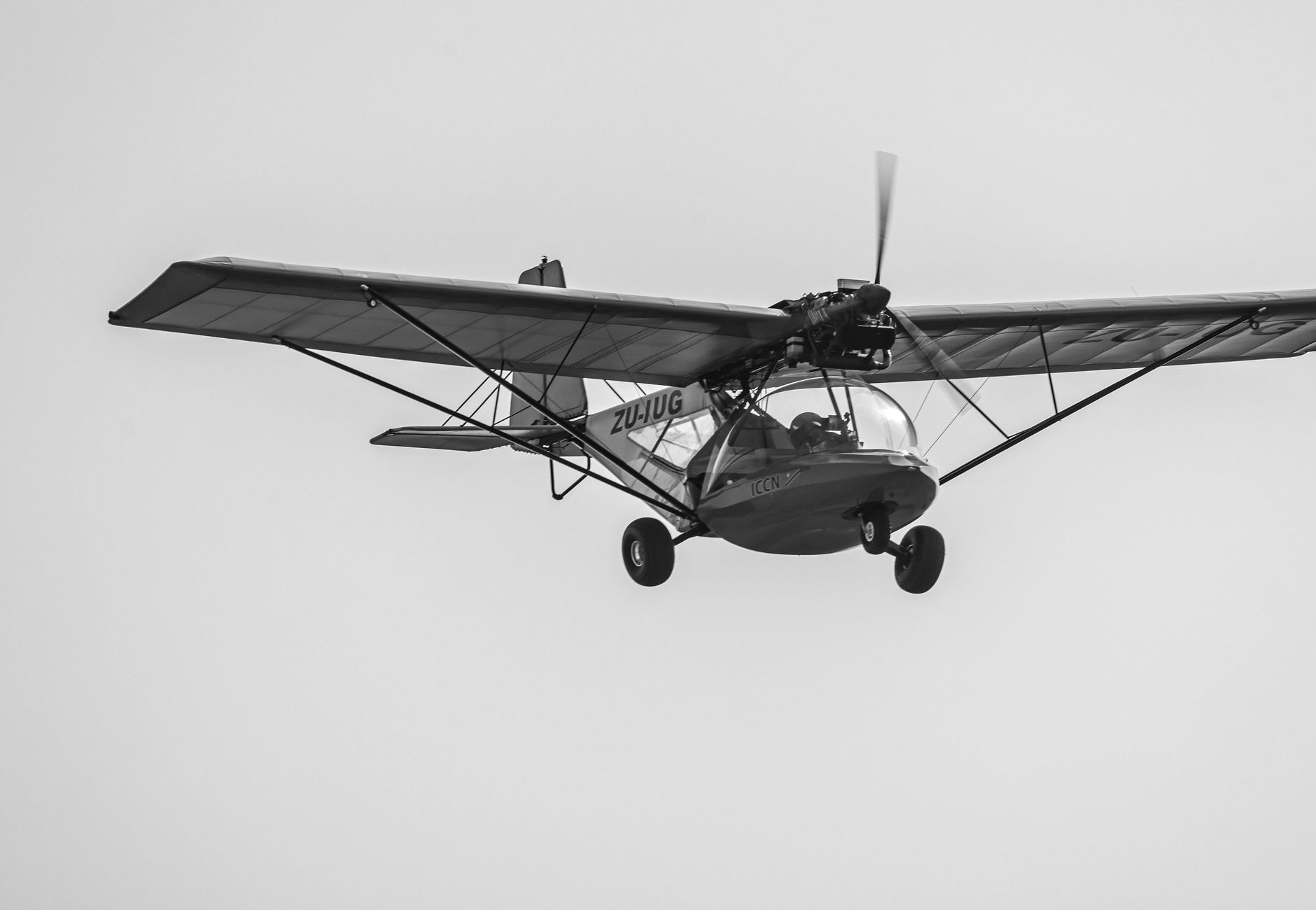 Black and white photo of a light aircraft in flight, highlighting its engineering and design.